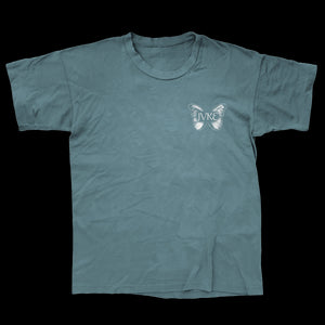 A plain teal JVKE Comfort Colors T-shirt with a small white butterfly graphic on the left chest, featuring JVKE letters inside the butterfly for a simple, stylish look.
