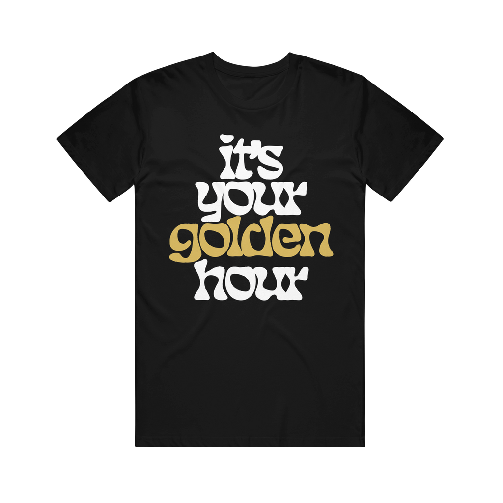 image of a black tee shirt on a transparent background. front has full body print in white that says it's your golden hour. the word golden is printed in gold shimmer ink